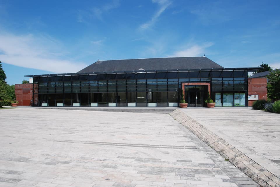 L'esplanade est prise de face, elle est entièrement couverte de pavés blancs. En fond, on aperçoit la salle des fêtes de Saint-Jean de Braye. 